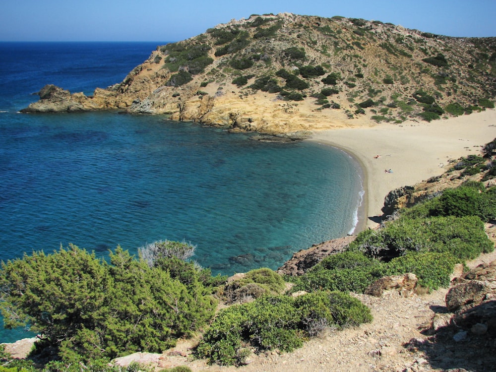 a sandy beach next to a blue body of water