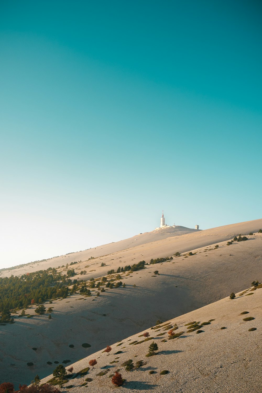 um farol branco no topo de uma colina no deserto