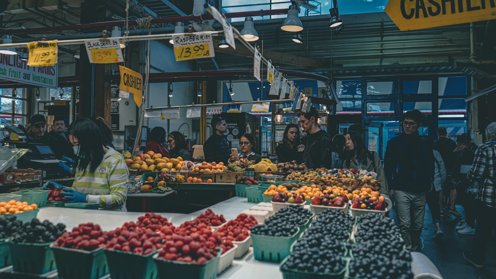 a group of people standing around a fruit stand