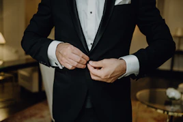 a man in a tuxedo tying his tie
