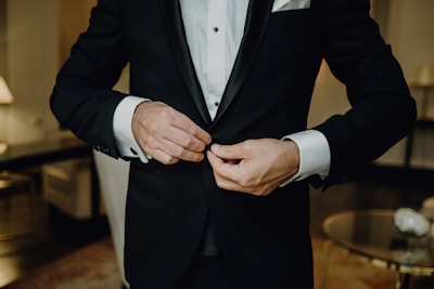 a man in a tuxedo tying his tie