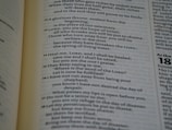 A close-up view of a page from a book, featuring text that appears to be biblical or poetic in nature. The text includes verses numbered sequentially, with some words in bold to emphasize importance. The background includes columns of text with clear typographic separation.