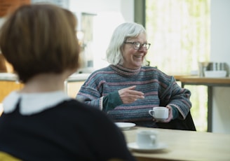 a woman sitting at a table talking to another woman