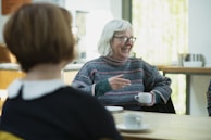 a woman sitting at a table talking to another woman