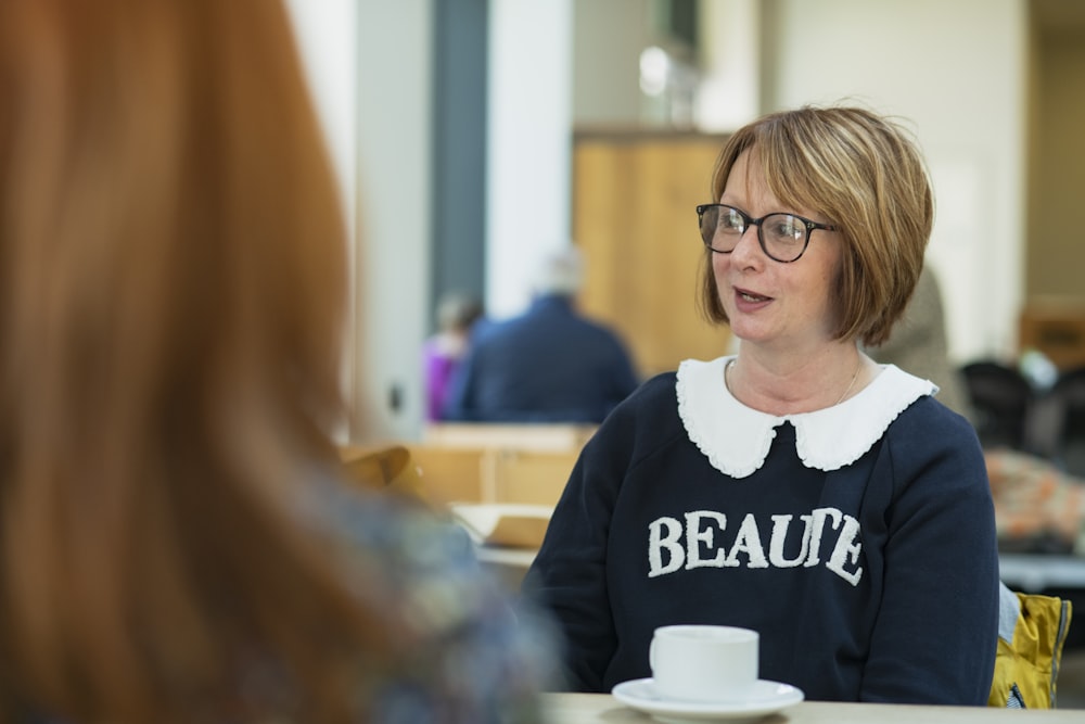 a woman sitting at a table with a cup of coffee