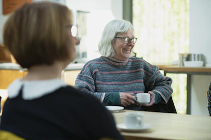 a woman sitting at a table with a cup of coffee