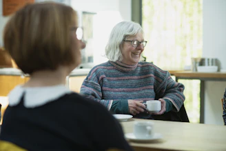 a woman sitting at a table with a cup of coffee