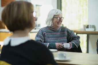 a woman sitting at a table with a cup of coffee