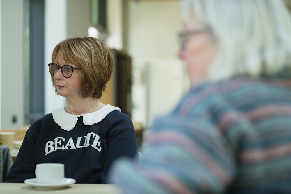 a woman sitting at a table with a cup of coffee