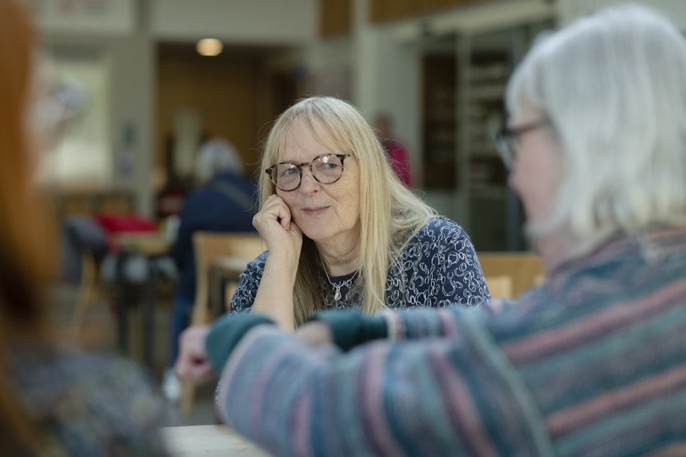 a woman sitting at a table talking to another woman