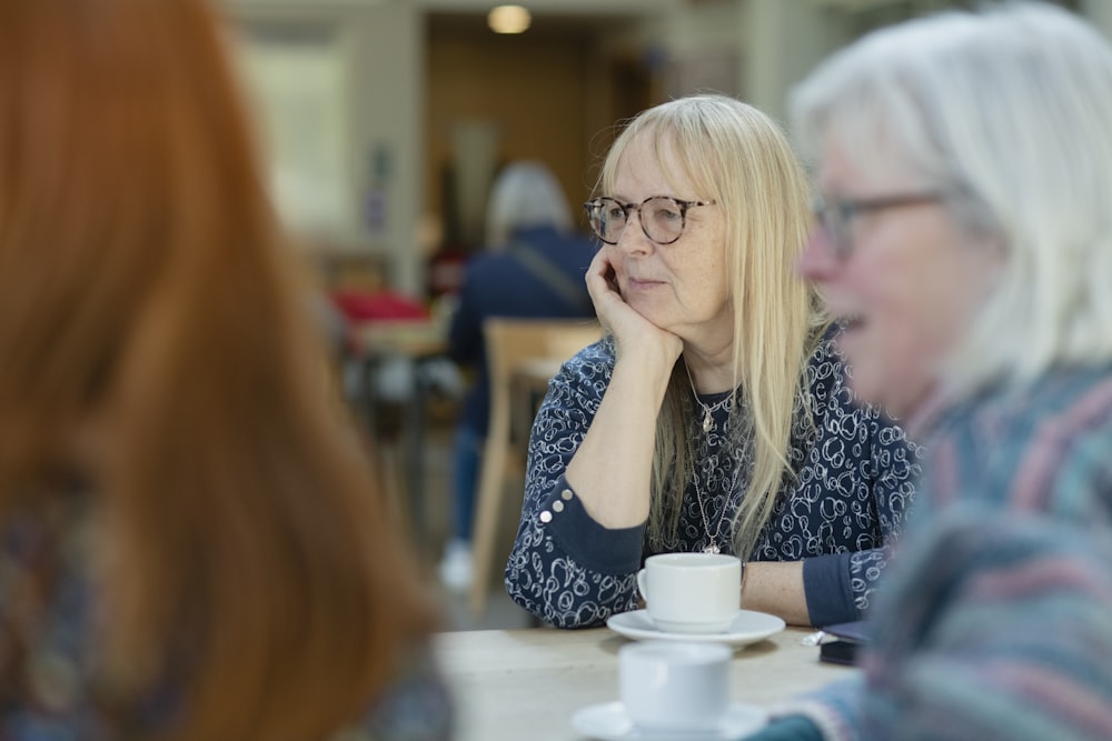 a woman sitting at a table with a cup of coffee