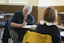 A smiling student practicing English conversation in a bright, modern classroom.