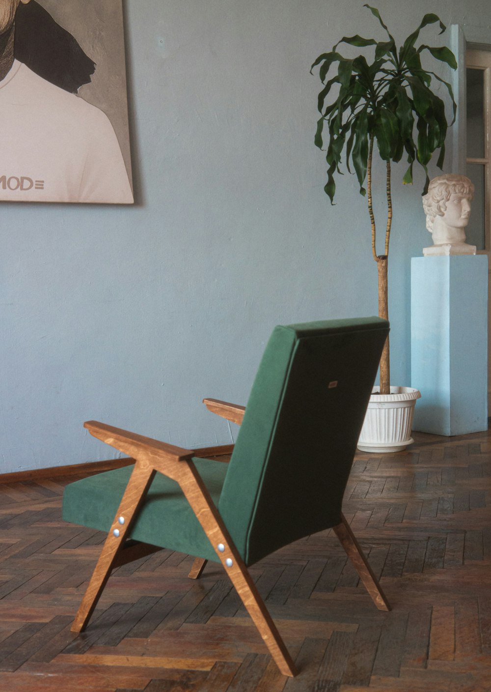 a green chair sitting in a room next to a potted plant