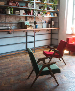 A cozy consultation room softly lit with warm green and beige tones, featuring a comfortable chair and a small bookshelf.