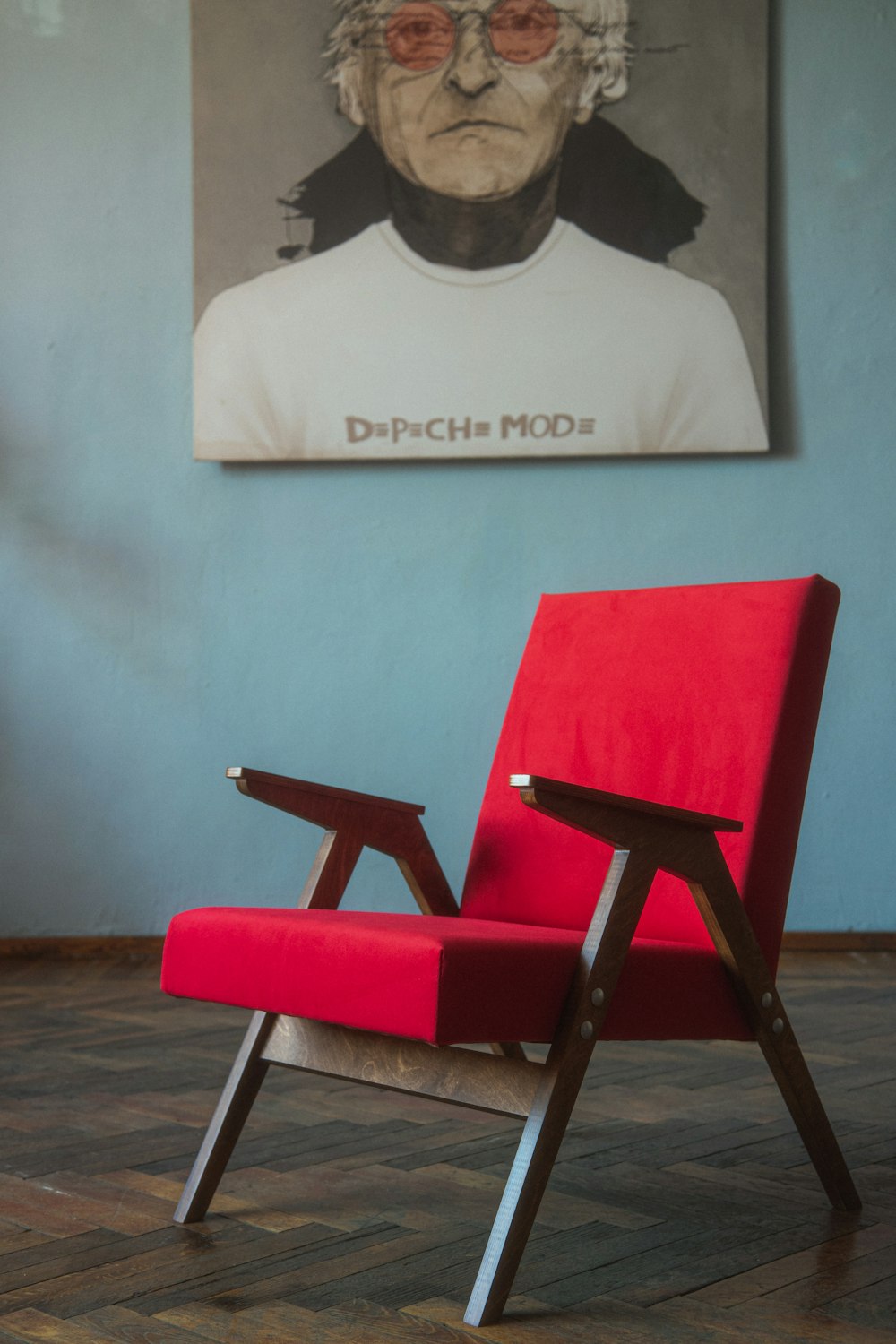 a red chair sitting in front of a painting