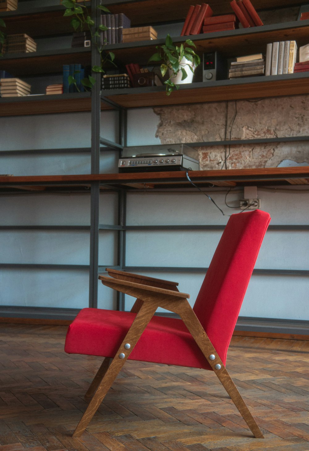 a red chair sitting in front of a book shelf