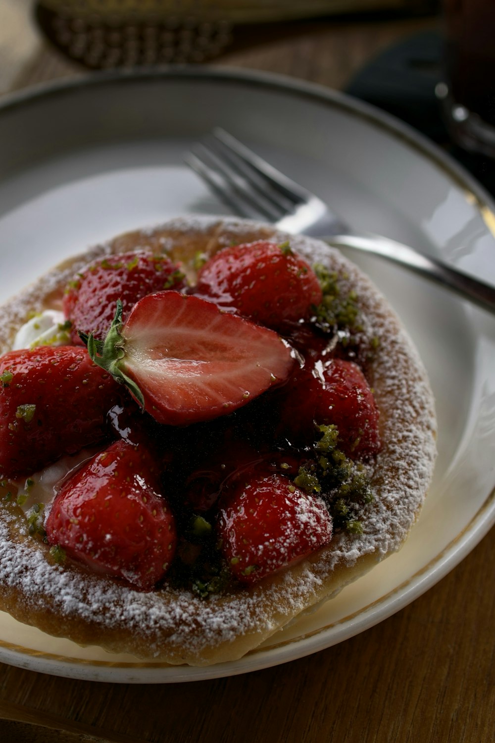 a white plate topped with a pastry covered in powdered sugar and sliced strawberries