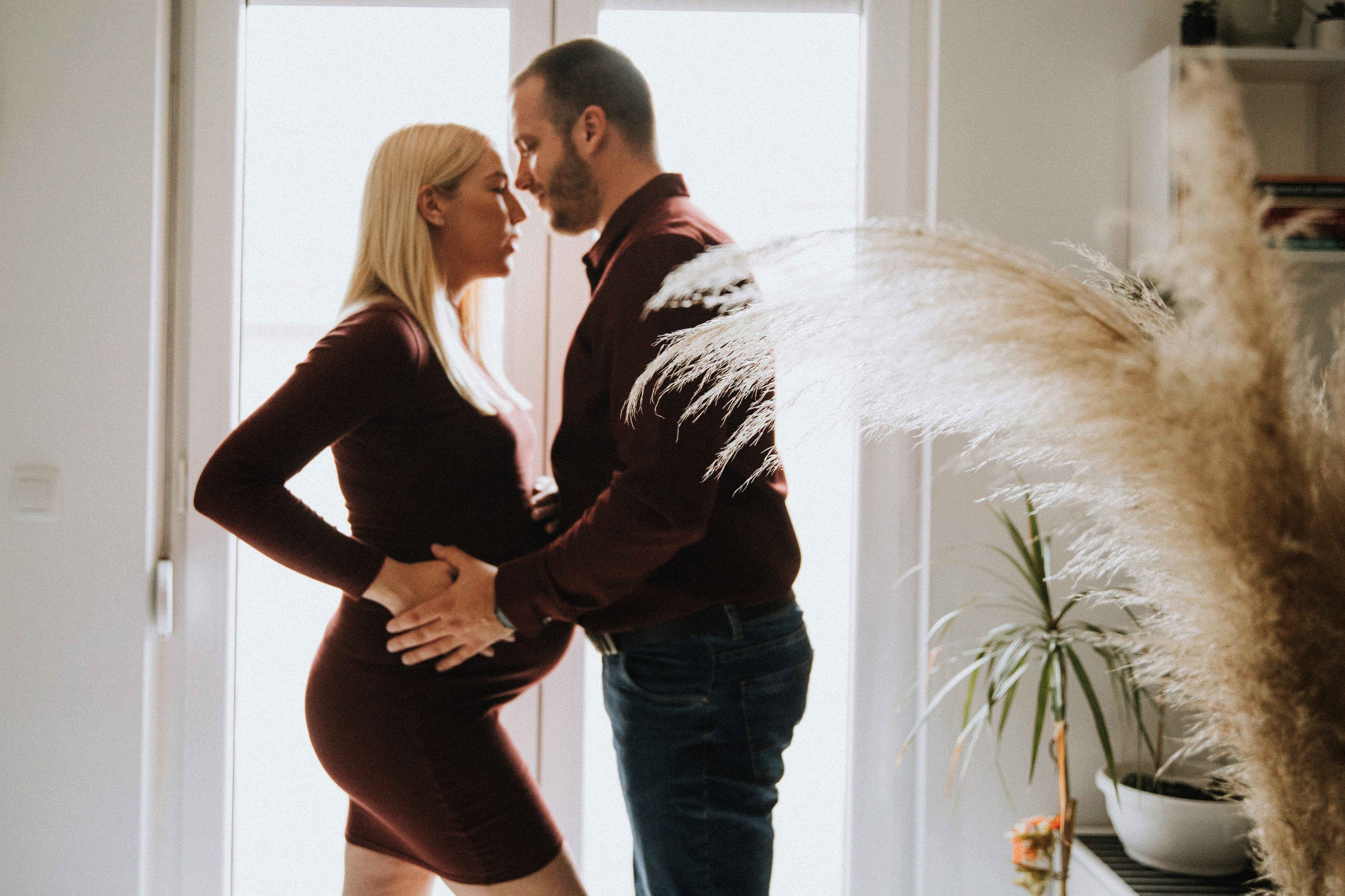 Expectant parents touching foreheads while holding the woman's belly.