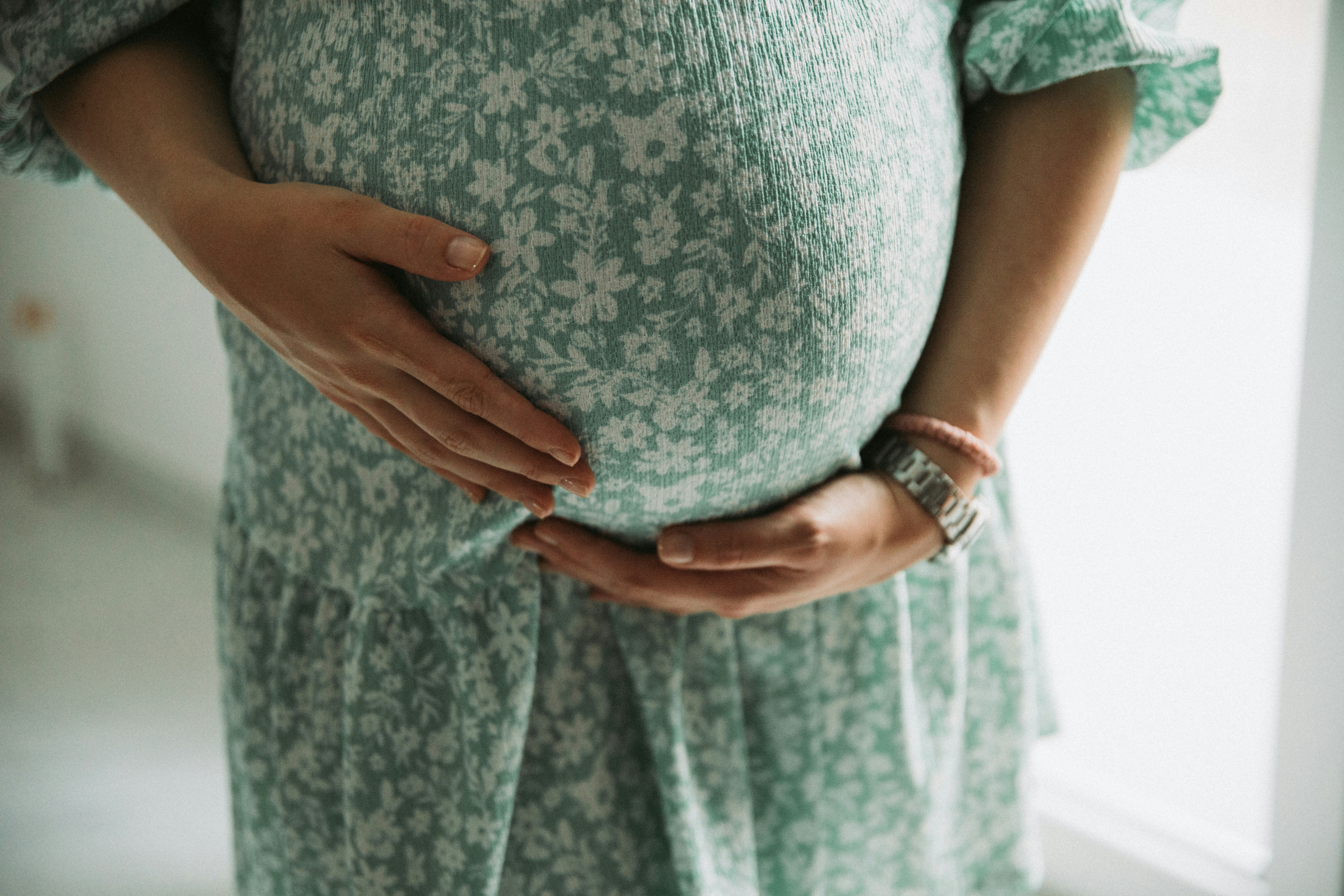 Pregnant woman holding her belly in a green dress