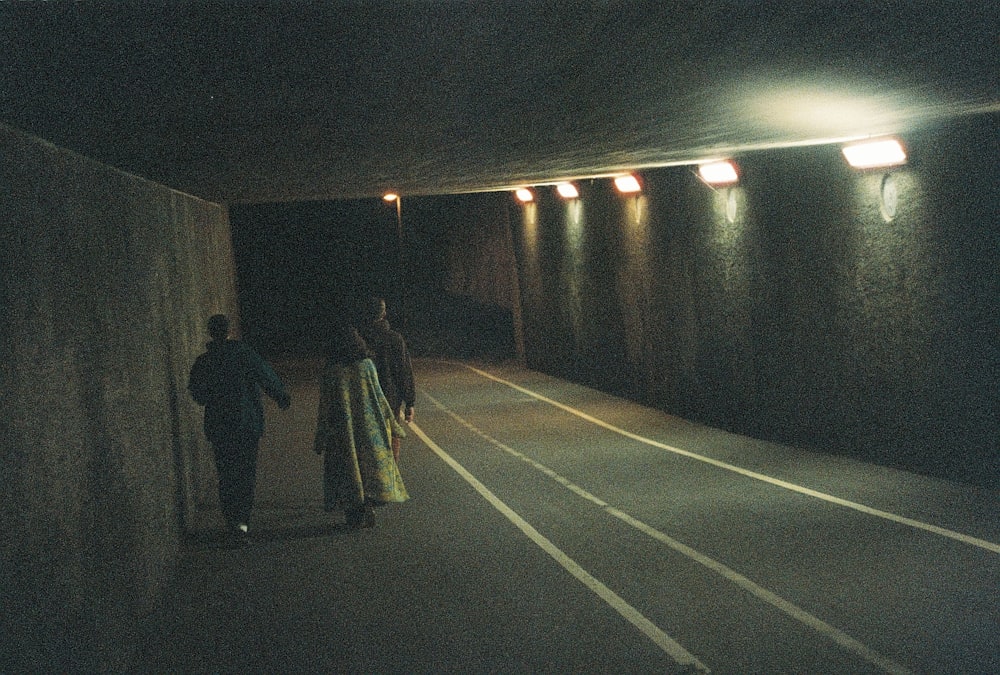 a couple of people that are walking down a tunnel
