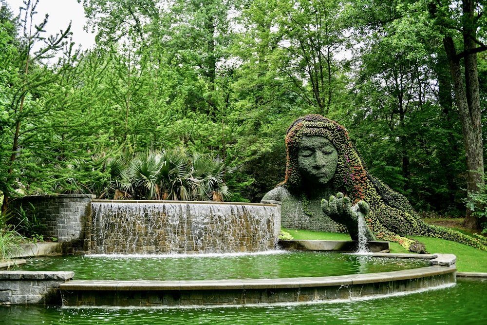 a statue of a woman is in the middle of a pond