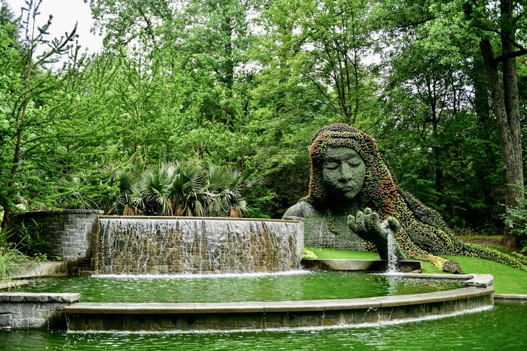 a statue of a woman is in the middle of a pond,