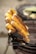 Charred ears of corn are stacked on a metal grill, showcasing a mix of golden yellow and dark brown colors from being roasted. The grill itself appears rustic and is likely part of a street food setup.