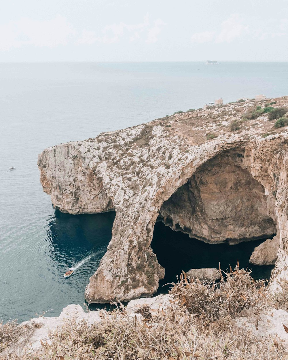 a large cave on the side of a cliff near the ocean