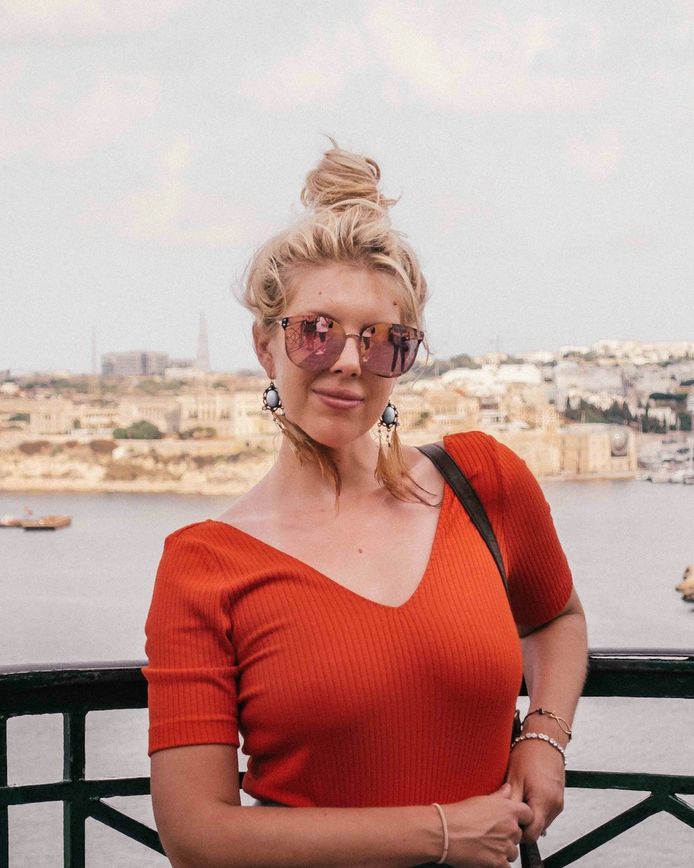 a woman in an orange top is posing for a picture