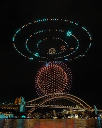 A stunning aerial view of a synchronized drone light show illuminating the night sky.