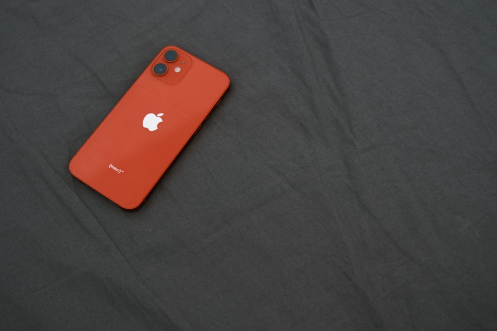 a red iphone is laying on a black surface