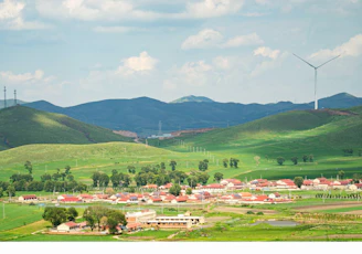 A panoramic view of a small wind farm beside a village, showing sustainable energy integration.
