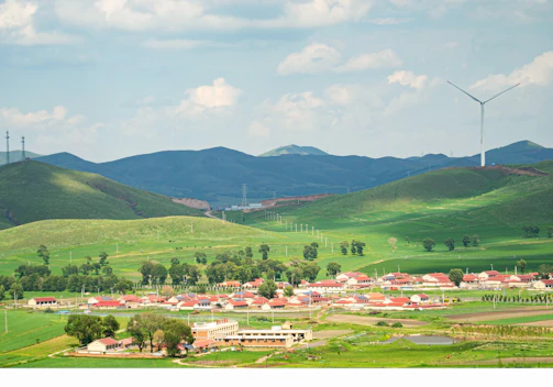 A panoramic view of a small wind farm beside a village, showing sustainable energy integration.