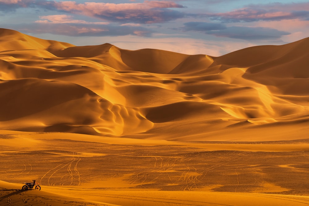 a truck driving through a desert with sand dunes