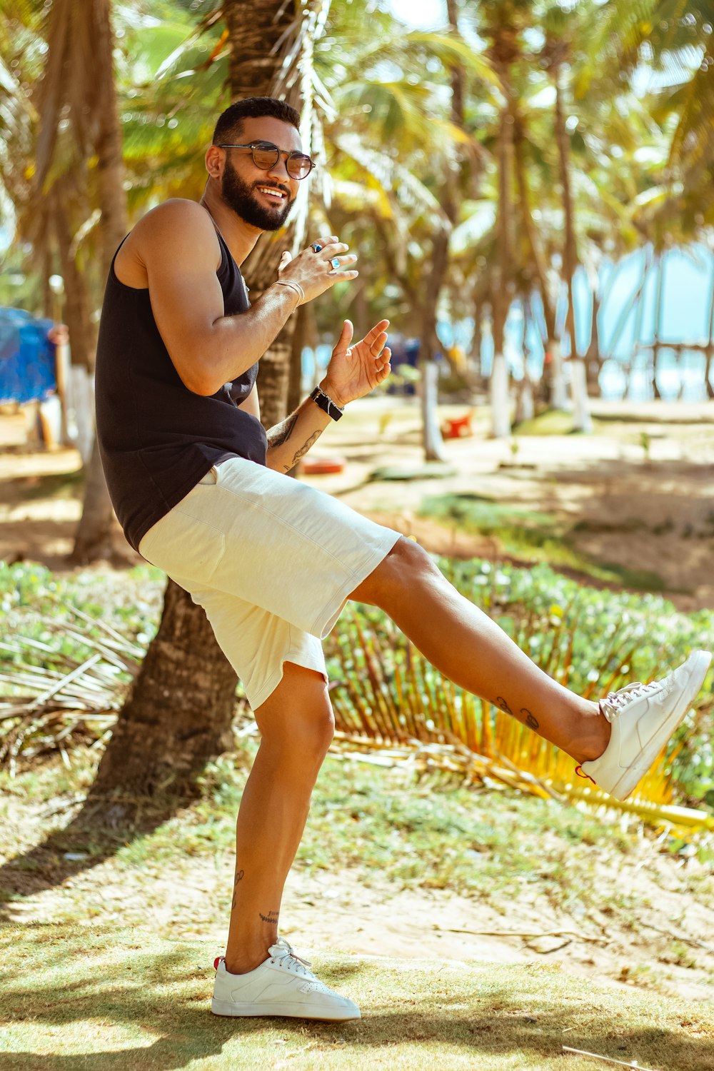 a man in a black tank top and white shorts kicking a soccer ball