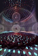A mesmerizing digital artwork featuring intricate geometric patterns with three large spherical structures at the center. The spheres appear to be composed of thin, transparent meshes surrounded by a vast array of glimmering, faceted elements reminiscent of crystalline forms. The scene is set within a reflective environment that amplifies the complexity and beauty of the design.