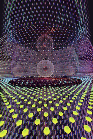 A visually complex scene featuring a symmetrical pattern with a central spherical object overlaid with a grid of glowing hexagonal shapes. The spherical object appears to be composed of intersecting lines, creating a wireframe look. The background is filled with a vibrant array of colors and reflections, giving a sense of depth and digital texture.