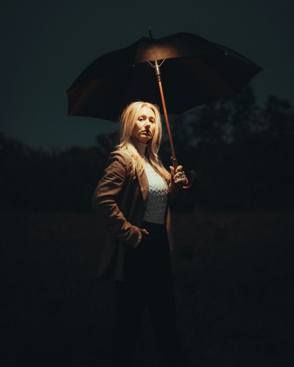 a woman standing in a field holding an umbrella