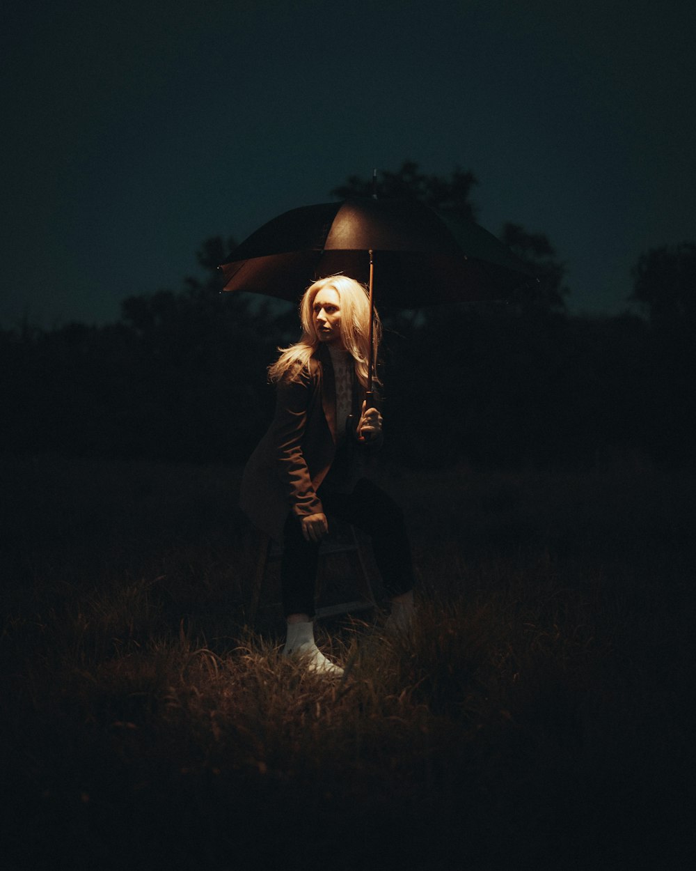 Una mujer parada en un campo sosteniendo un paraguas