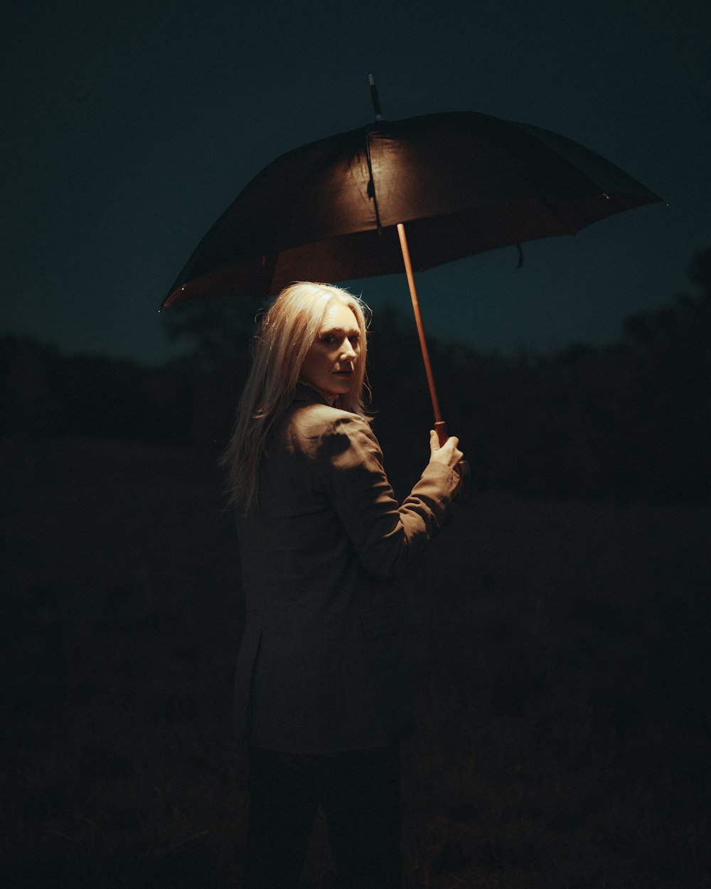 a woman standing in a field holding an umbrella