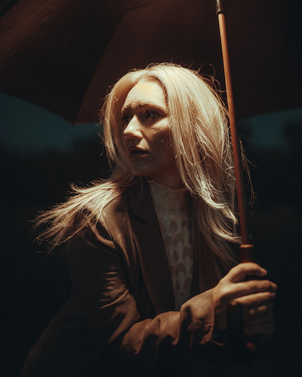 a woman with long blonde hair holding an umbrella