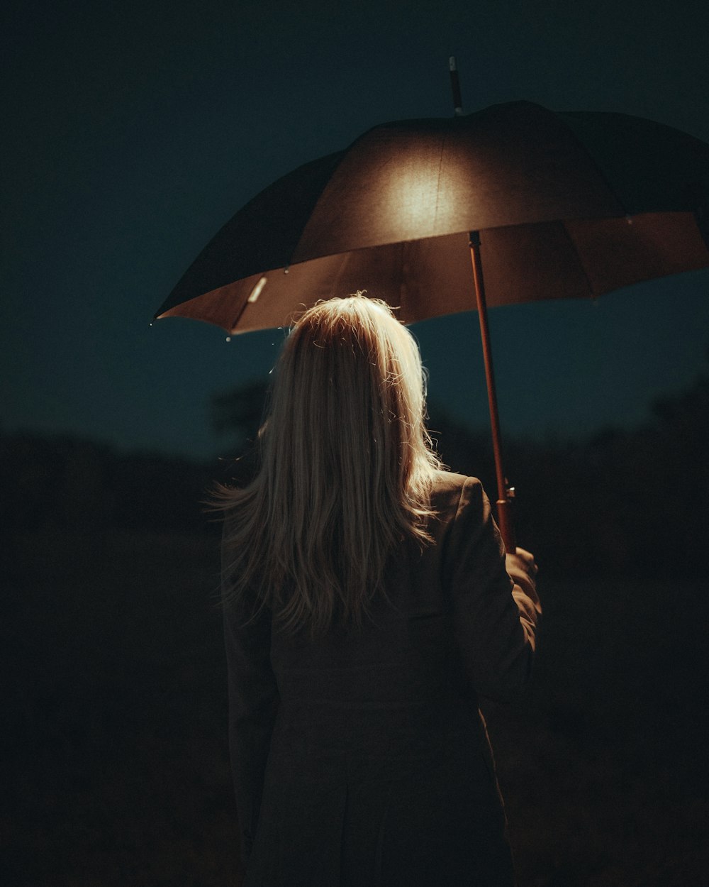 a woman holding an umbrella in the dark