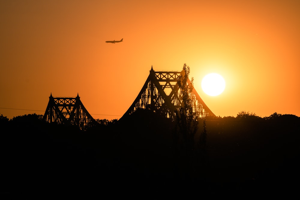 a plane is flying over a bridge at sunset