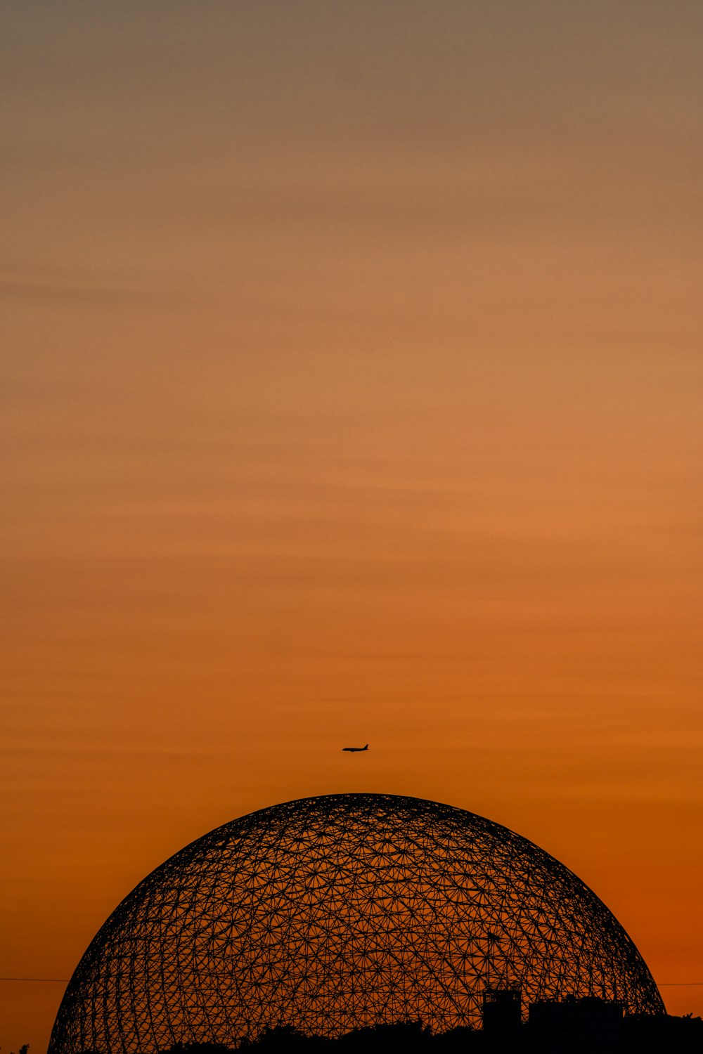 a plane flying in the sky over a dome