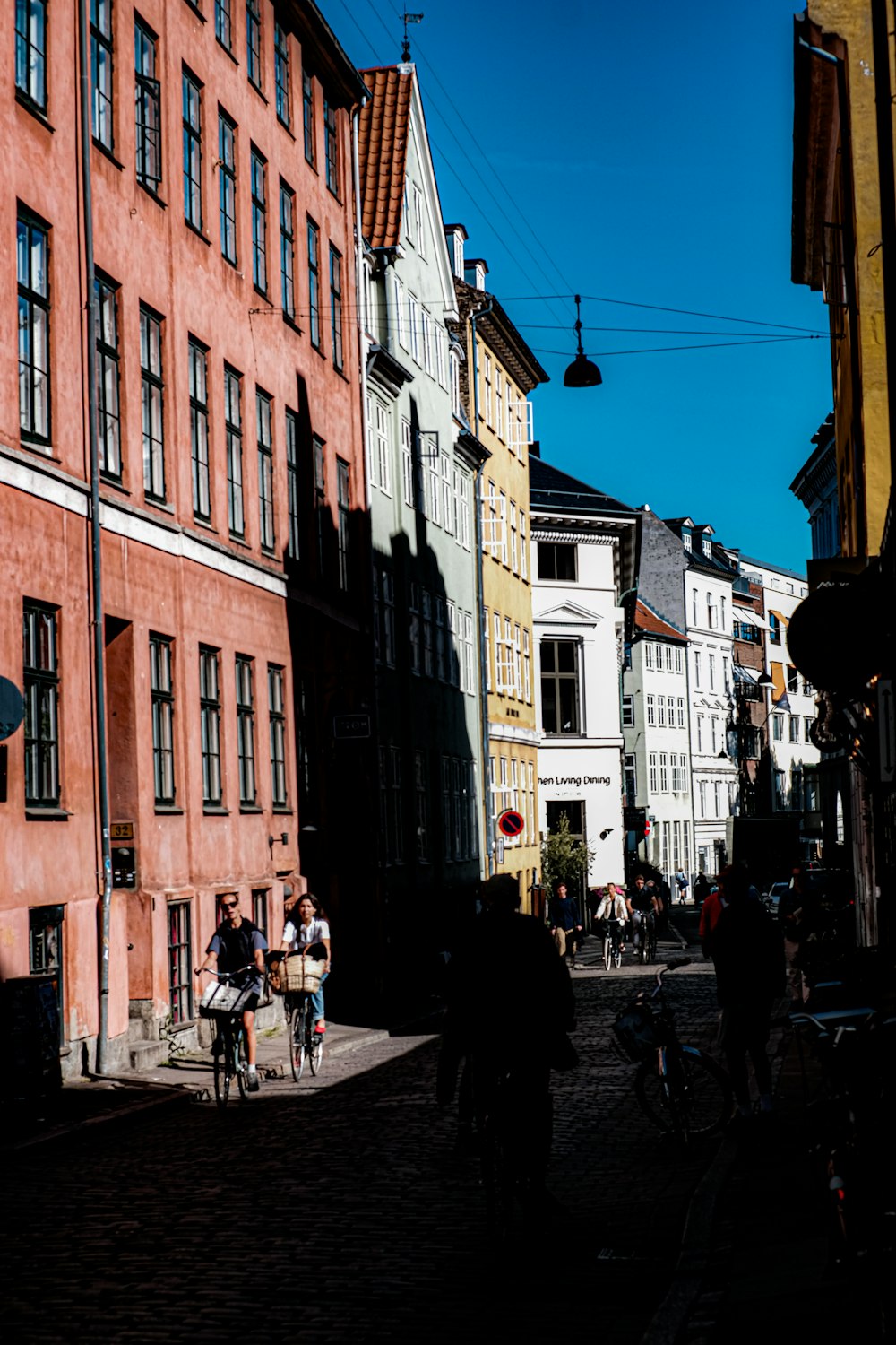 a group of people walking down a street next to tall buildings