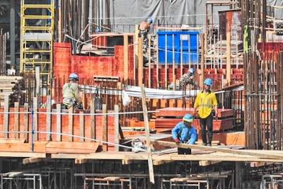 Construction workers in helmets and vests collaborating on a marine construction site.