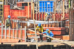 Construction site with heavy machinery and workers in safety gear building infrastructure.