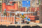 Construction site with heavy machinery and workers in safety gear building infrastructure.