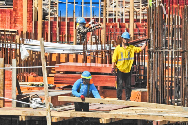 A group of construction workers in safety gear collaborating on a building site in Al Jubail.