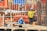 Three construction workers wearing safety gear and hard hats are actively engaged in building activities at a construction site. They are surrounded by metal rebar, wooden planks, and other construction materials.